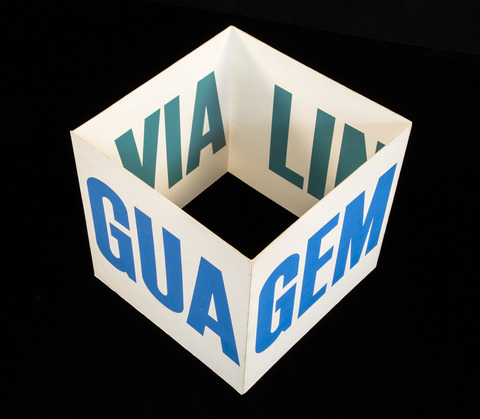 A large standing "cubepoem" (printed text on heavy paper folded into a square) with text on the interior and exterior faces spelling the invented word Linguaviagem.